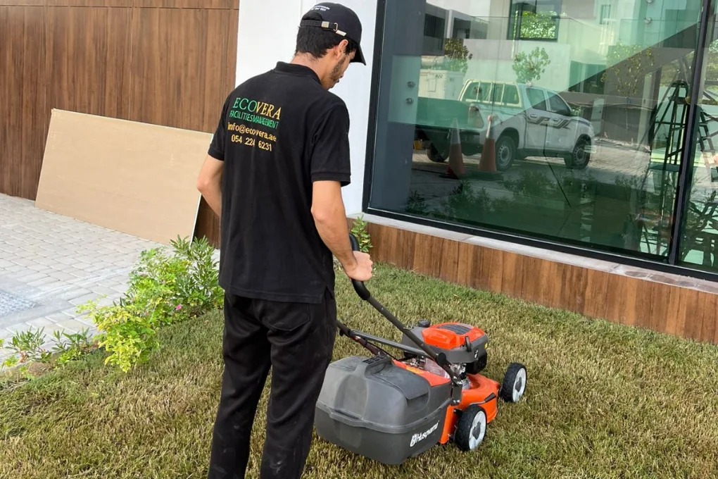 A groundskeeper mowing a landscaped lawn